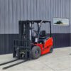 A red forklift parked in front of a building.