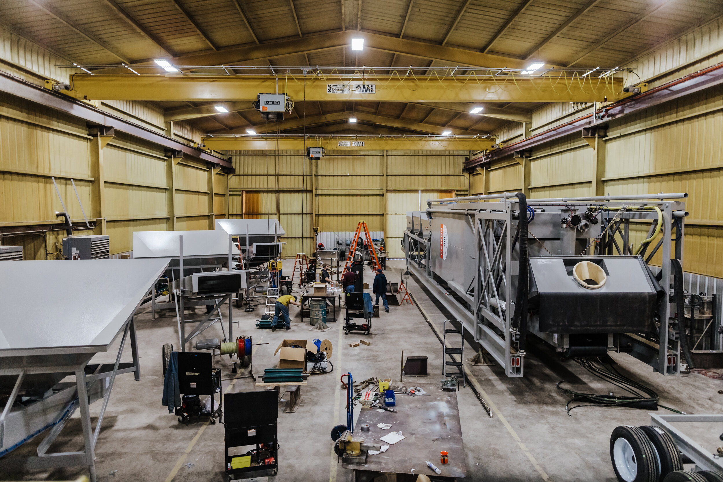 A large warehouse with many workers working on machinery.