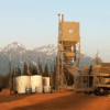 A large cement plant with mountains in the background.