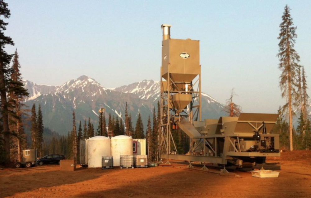 A large cement plant with mountains in the background.